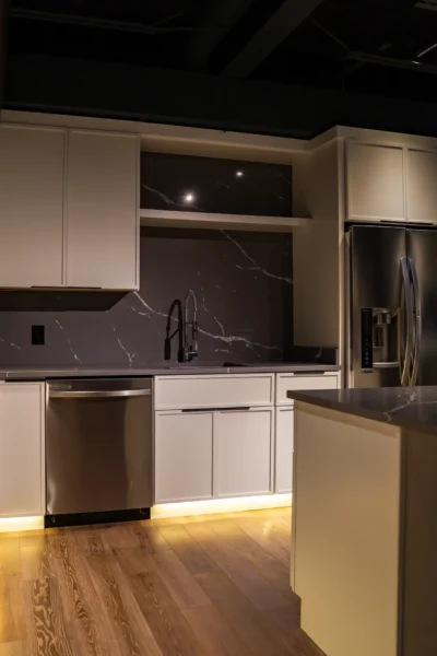 Contemporary kitchen with white cabinetry, dark marble backsplash, and stainless steel refrigerator
