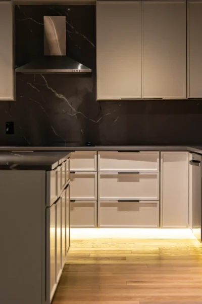 Modern kitchen with white cabinets, dark marble backsplash, and stainless steel dishwasher