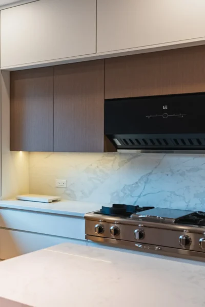 Close-up of modern kitchen cooktop with marble backsplash and under-cabinet lighting