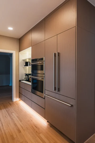 Modern kitchen wall with built-in refrigerator, double oven, and wood cabinetry