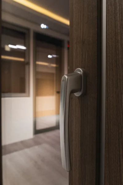 Close-up of modern window handle on wood frame with showroom interior background